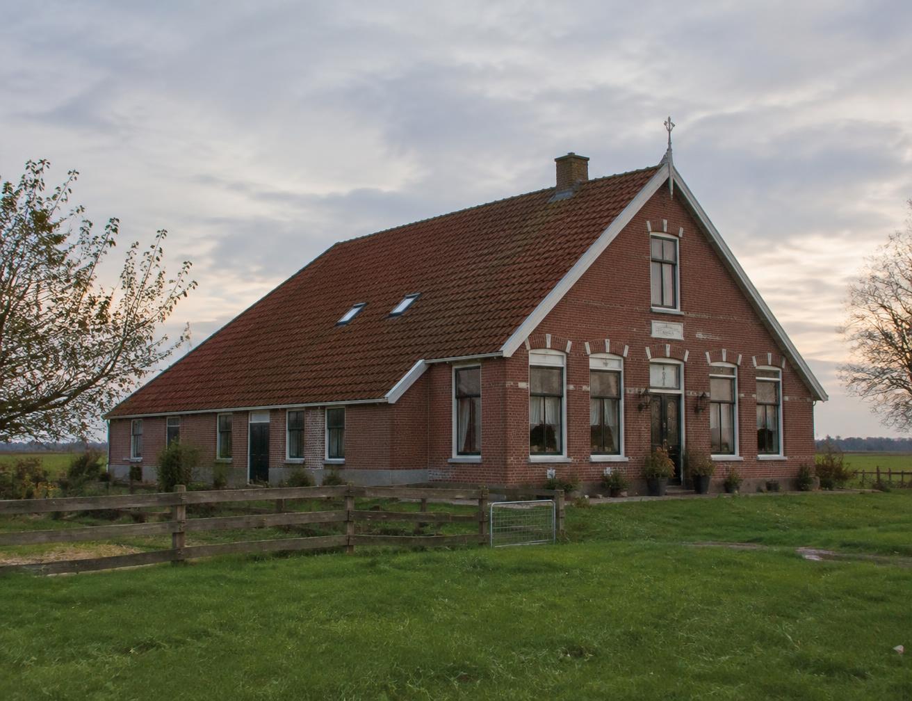 Groningse boerderij van rode baksteen in het open landschap